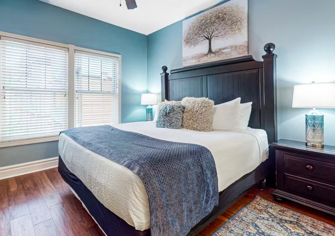 Unwind in your tranquil bedroom featuring soft blue walls, plush bedding, and warm hardwood floors that create the perfect retreat.