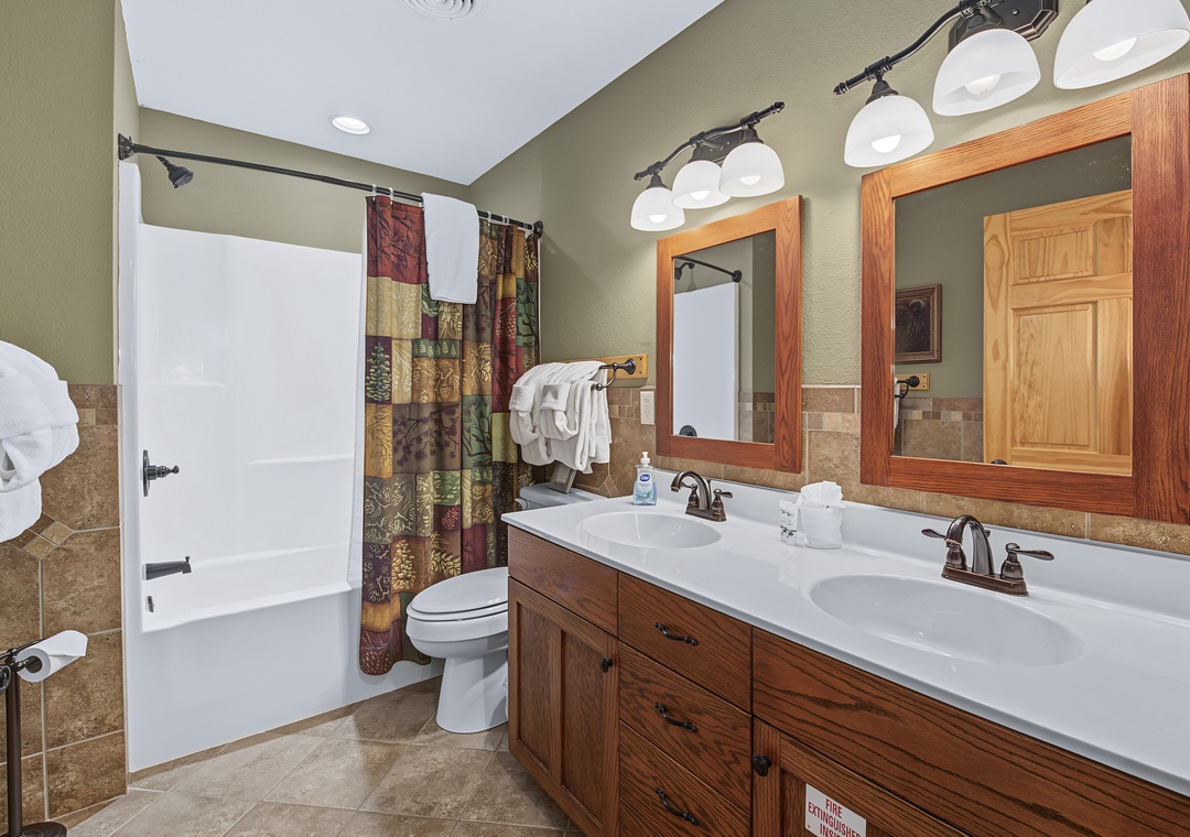 Your spacious bathroom features a double vanity with warm wood tones, a tub-shower combo, and thoughtful lighting—perfect for refreshing after a day of adventure.