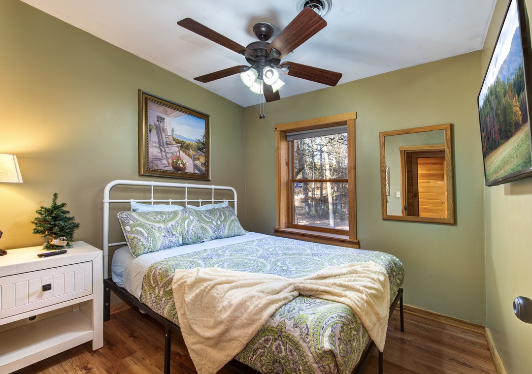 Your cozy bedroom retreat features calming green walls, comfortable bedding, and a ceiling fan to keep you cool during restful nights.