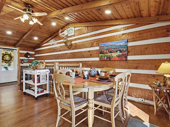 Gather around the charming wooden table under warm cabin ceilings where rustic character meets comfort, inviting you to share meals and make memories in this cozy, welcoming dining space.