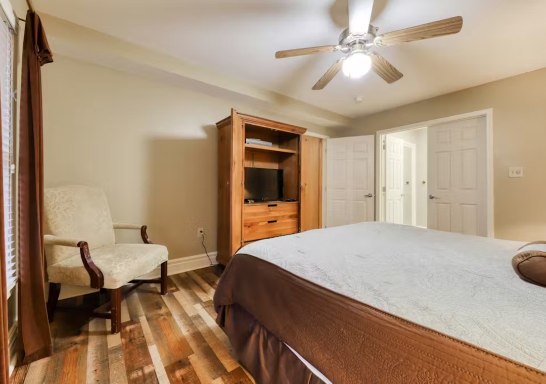Relax in your comfortable bedroom with warm wood details, elegant seating area, and entertainment center for perfect evening unwinding.