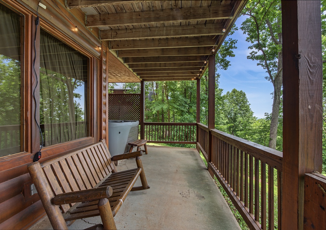 Settle into this peaceful covered deck overlooking lush forest views, where rustic wood furnishings invite you to unwind in nature's tranquil embrace.