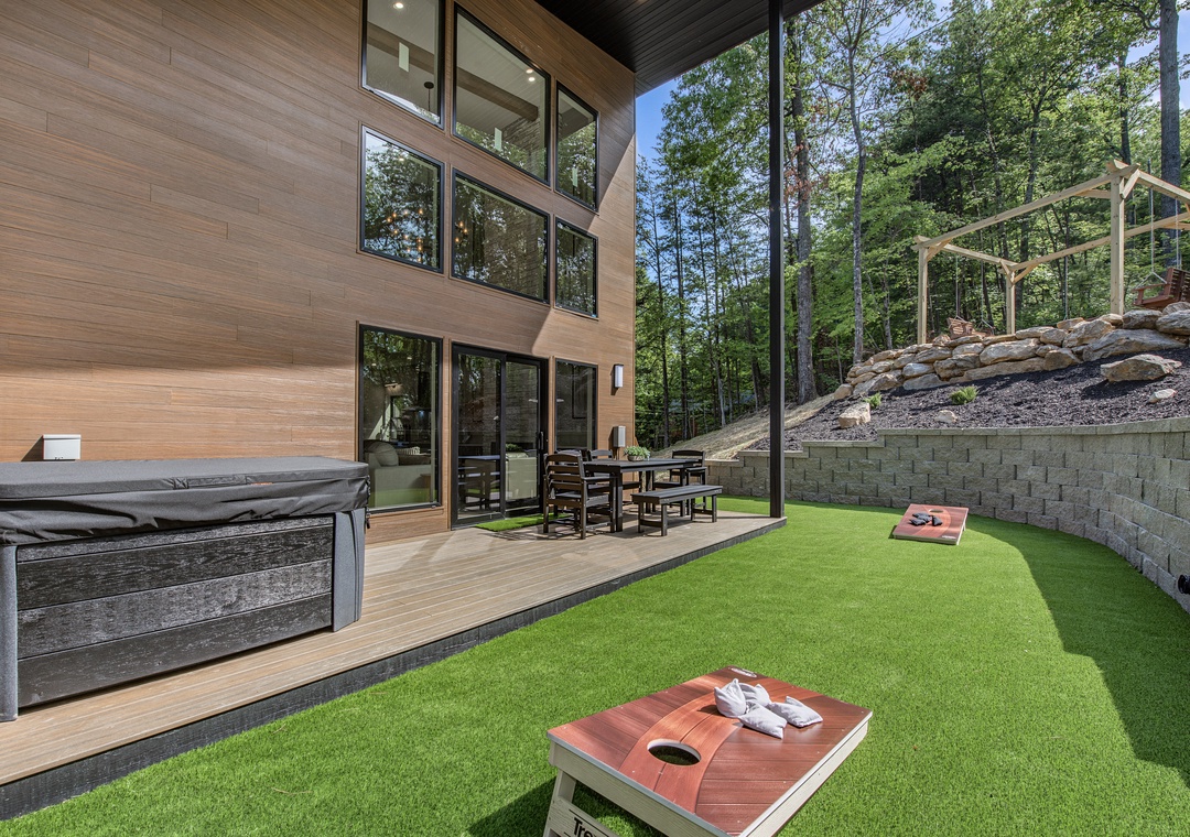 Step outside to your private backyard oasis where endless fun awaits on the turf lawn with cornhole, deck dining, and hot tub relaxation under towering trees.