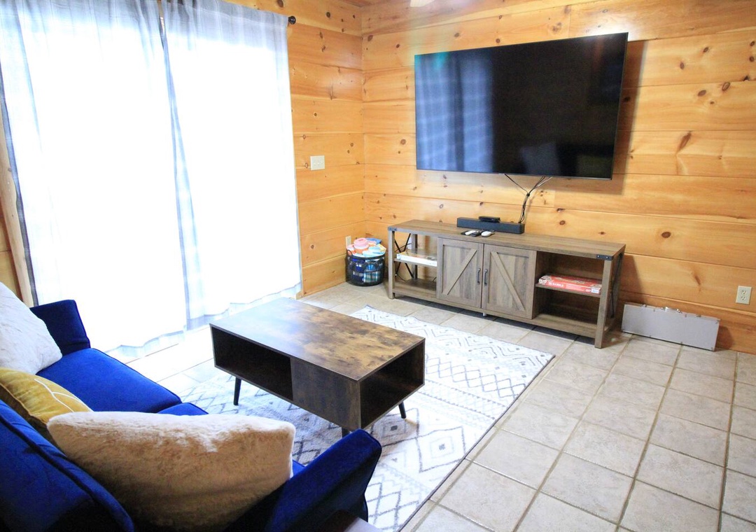 Cozy up in your rustic living room with warm wood walls, comfortable seating, and a large TV for movie nights.