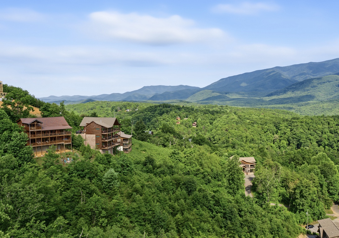 Mountain resort cabins nestled among lush forest with expansive views of rolling peaks and valleys in the surrounding area.