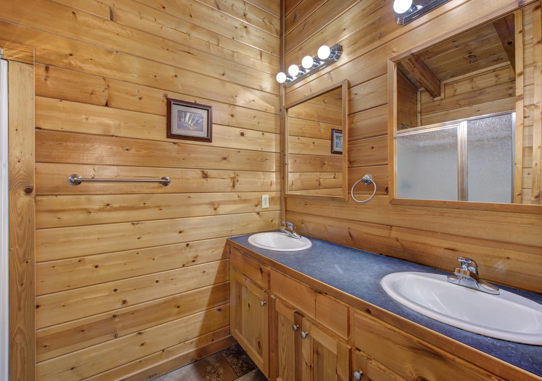 Step into your rustic log cabin bathroom with warm wood walls and dual sinks for convenient morning routines.