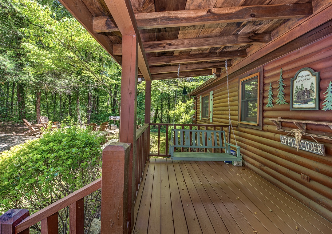 The covered porch invites you to slow down on the swing, surrounded by lush woods and the warm charm of the log cabin's rustic details.