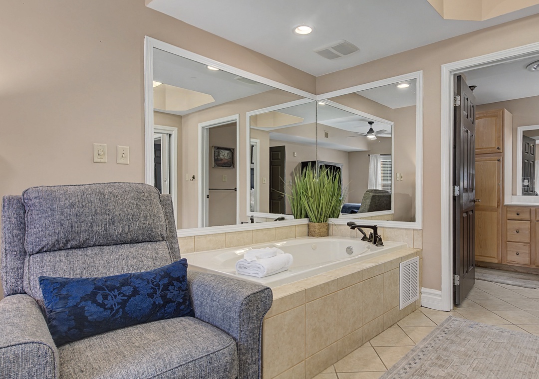 Unwind in your spa-like bathroom with soaking tub, plush seating area, and elegant mirrors for ultimate relaxation.