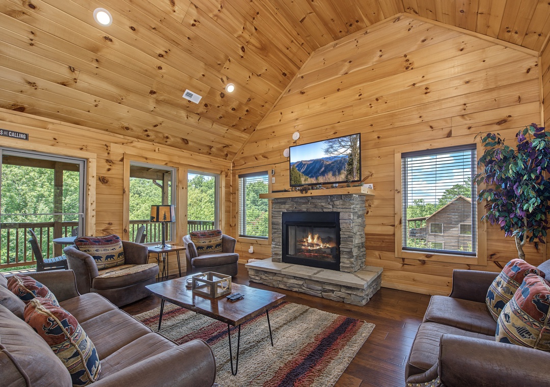 Gather around your cozy stone fireplace in this warm, inviting living room with vaulted wood ceilings and comfortable seating for the whole family.