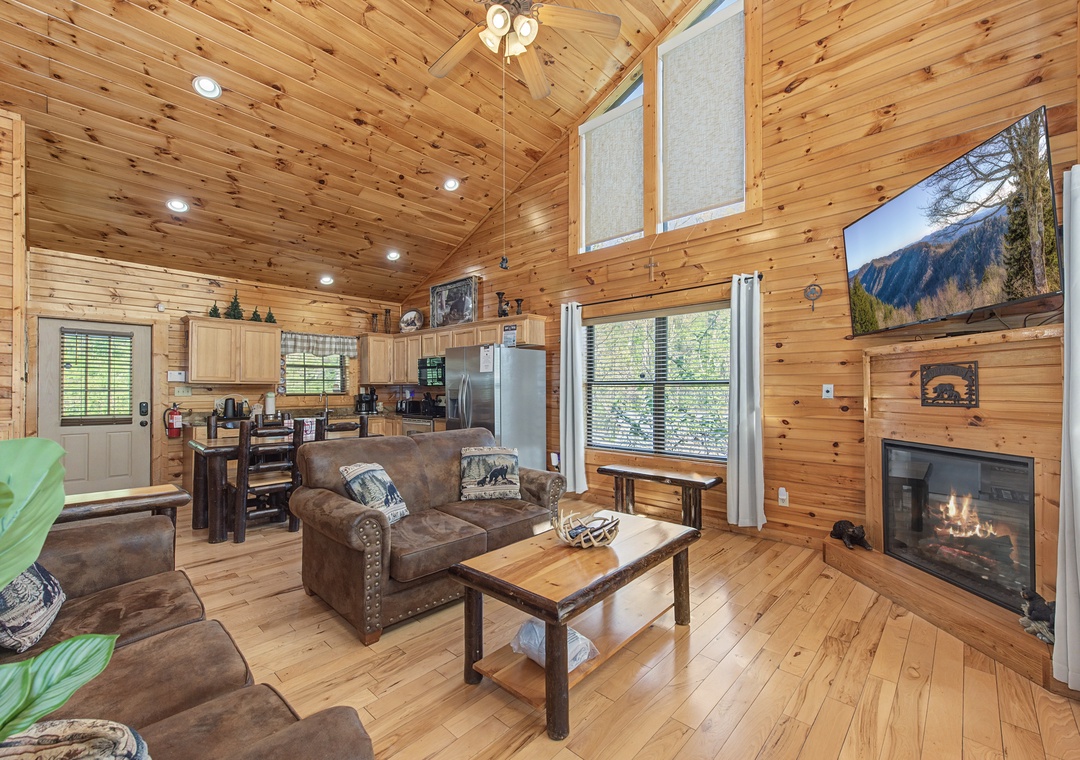 Relax in your cozy cabin's open living space, where warm wood surrounds you and a fireplace creates the perfect mountain retreat atmosphere.