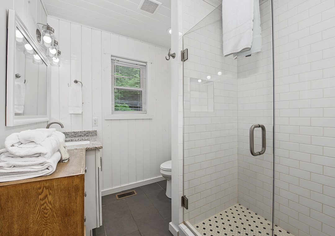 Step into your private bathroom, where crisp white subway tiles and modern fixtures create a spa-like retreat. Fluffy towels await, and the spacious walk-in shower invites you to refresh after your adventures.
