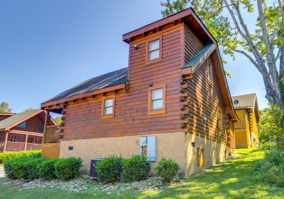 Charming log cabin exterior nestled among mature trees in a peaceful residential setting.