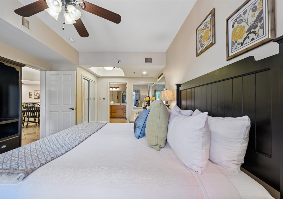Sink into plush bedding and let the ceiling fan's gentle breeze lull you to sleep in this serene bedroom suite, featuring an elegant black headboard and cozy en-suite access.