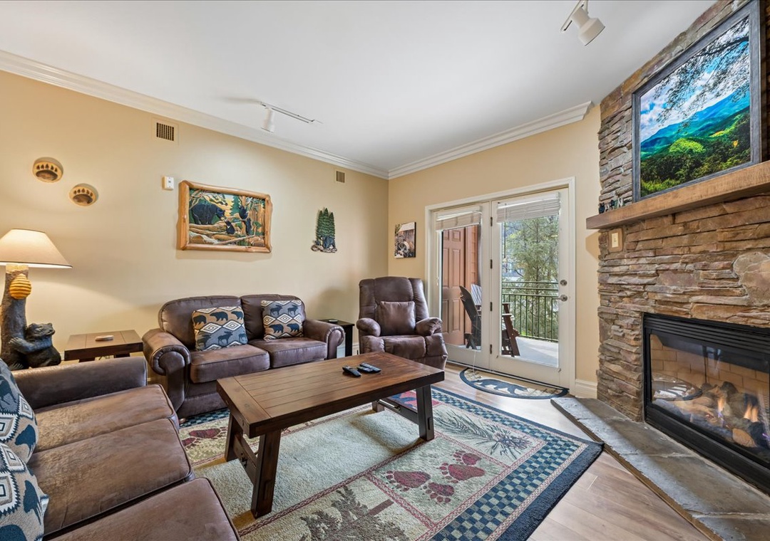 Unwind in your cozy living room featuring plush leather seating, a crackling fireplace, and scenic balcony access.
