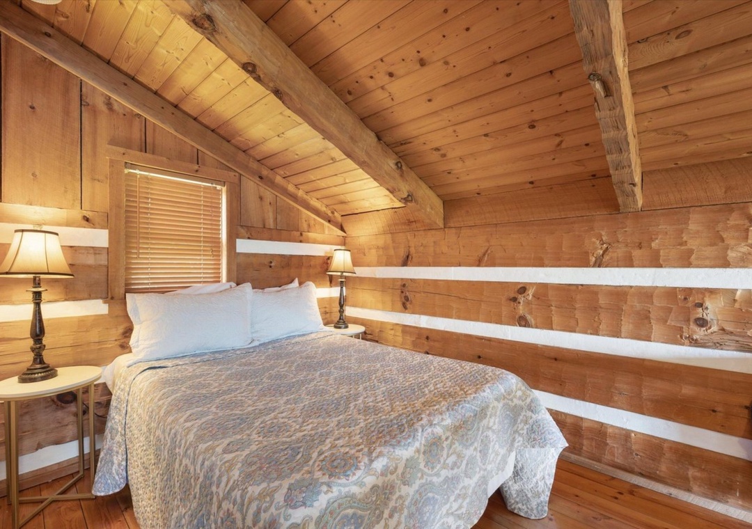 Cozy log cabin bedroom with warm wood walls and rustic charm invites peaceful mountain retreat sleep under exposed beam ceilings.