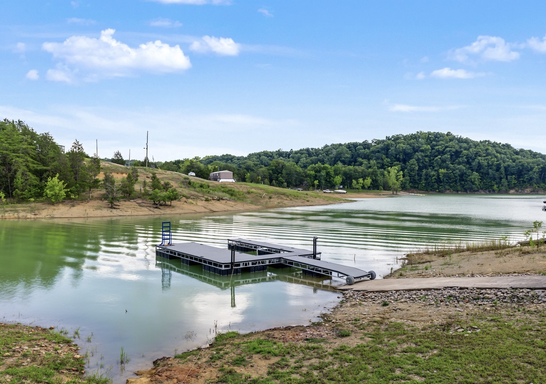 A private dock on a tranquil lake surrounded by rolling green hills and natural landscape, offering serene waterfront access during your stay.