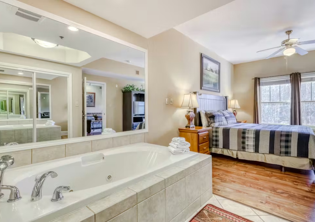 Unwind in your luxurious master suite featuring a romantic jetted tub and cozy bedroom with warm wood floors.