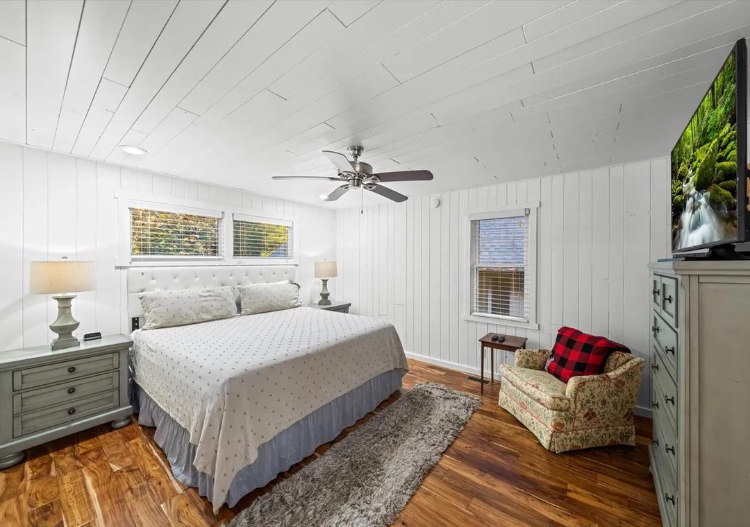 Step into your bright and airy bedroom, where white shiplap walls and warm hardwood floors create the perfect retreat. The ceiling fan keeps you cool while you relax in the cozy armchair or unwind in your comfortable bed.