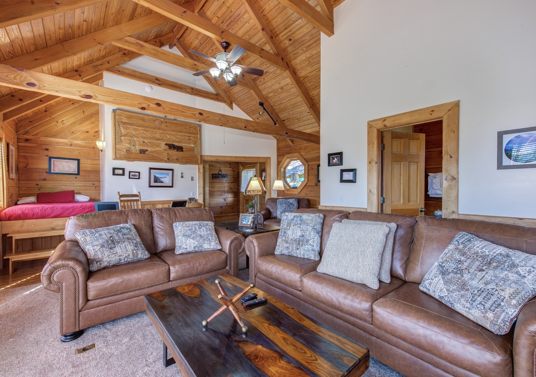 Sink into plush leather sofas beneath soaring wood beams where rustic charm meets comfort in your mountain retreat's cozy living space.