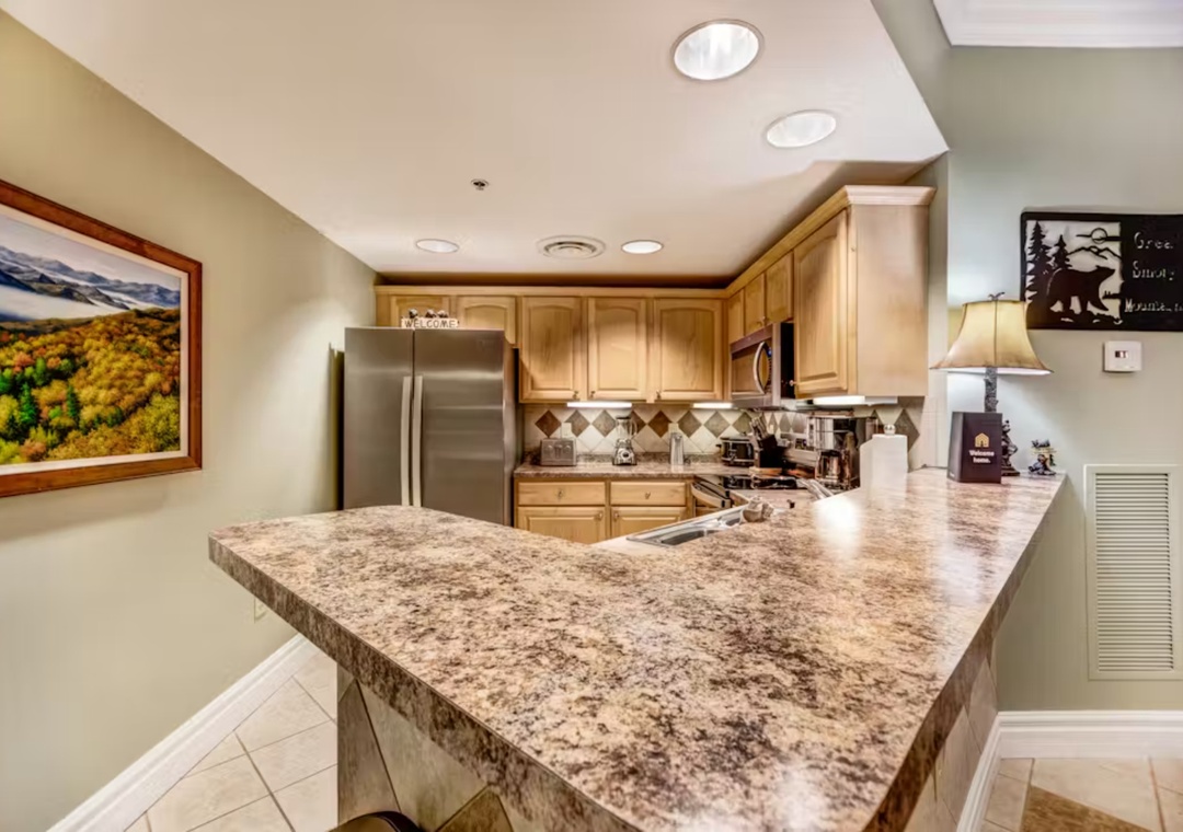 Your fully equipped kitchen features granite countertops, stainless steel appliances, and warm wood cabinetry perfect for preparing meals together.