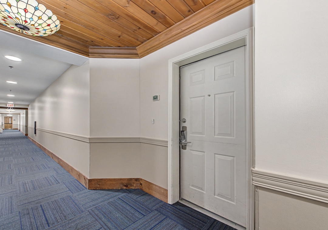Your suite awaits behind a keyless entry door along elegant wood-accented hallways with artistic ceiling details.