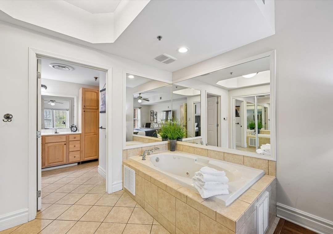 Unwind in your private spa-like bathroom with a luxurious soaking tub surrounded by elegant mirrors and fresh towels awaiting your arrival.
