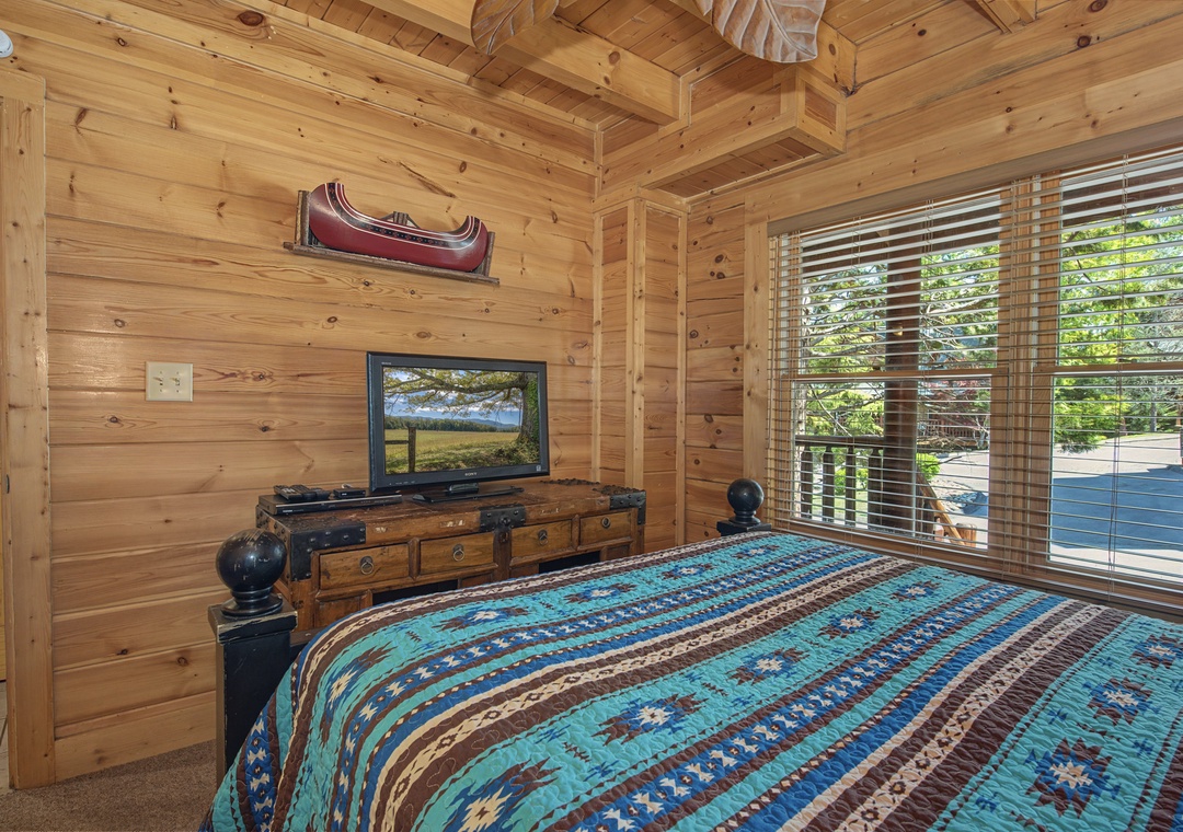 Cozy cabin bedroom with rustic charm and TV for your evening relaxation after mountain adventures.