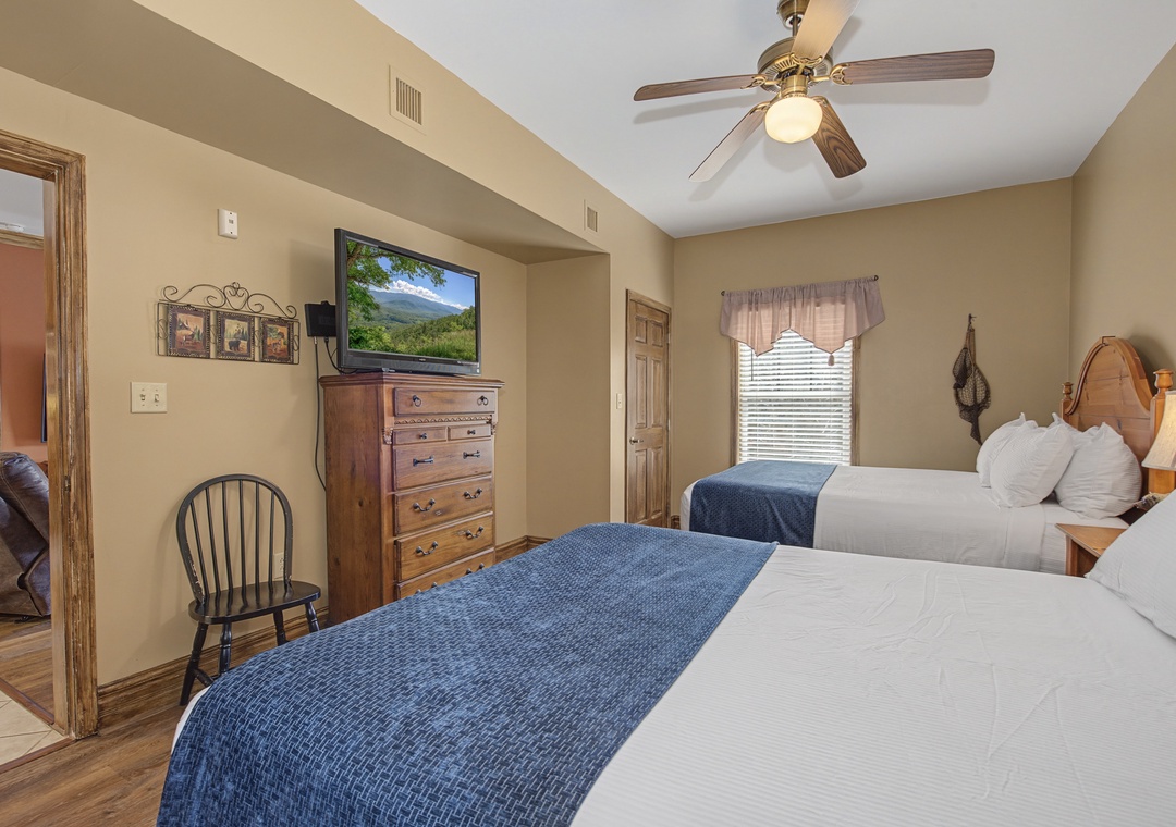 Rest easy in your comfortable twin bedroom with plush bedding, entertainment center, and warm mountain lodge charm.