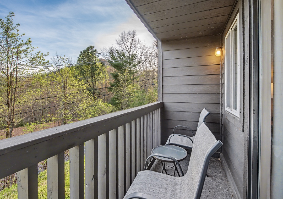 Relax on your private balcony with comfortable seating overlooking peaceful wooded views.