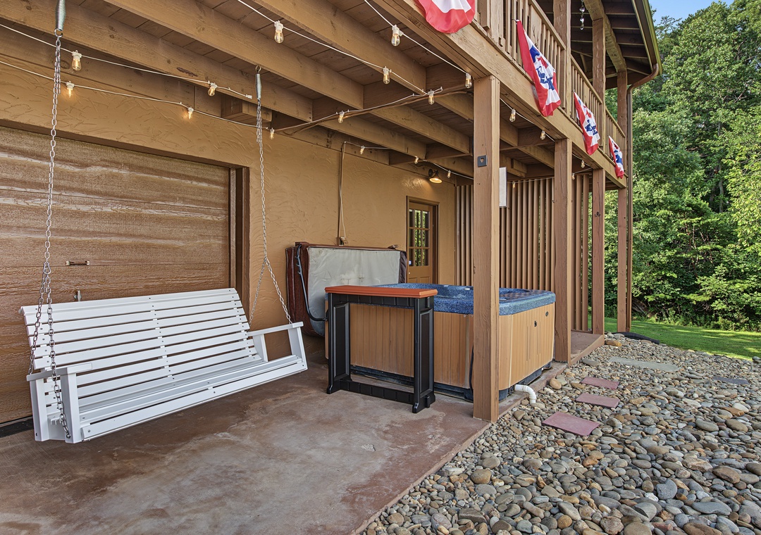 Picture yourself unwinding on this inviting porch swing after a day of adventure. String lights create a warm ambiance while the hot tub beckons you to relax under the trees.