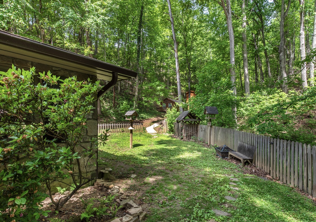 Nestled in the woods, this private backyard offers a peaceful retreat surrounded by towering trees and natural greenery, perfect for unwinding in nature's embrace.
