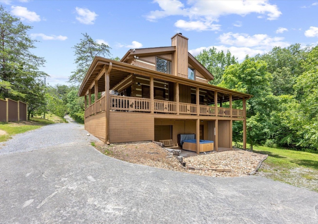 Modern log cabin nestled among lush forest with wraparound deck and convenient paved parking.