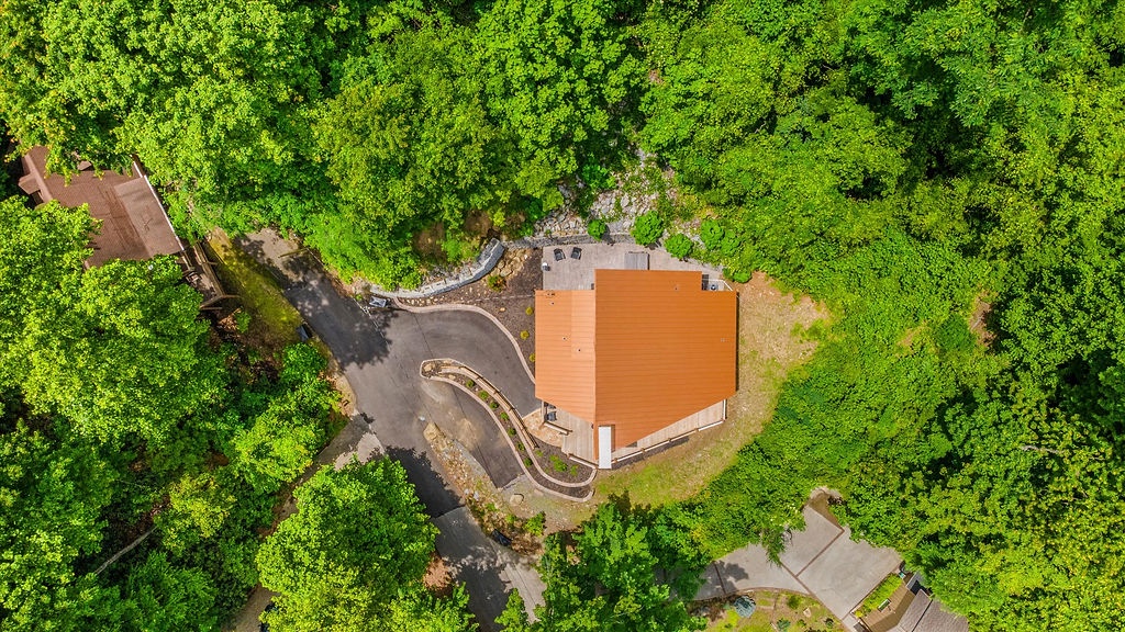 Aerial view showcasing the property nestled in lush forest surroundings, offering a secluded natural setting with easy access via a winding private driveway.