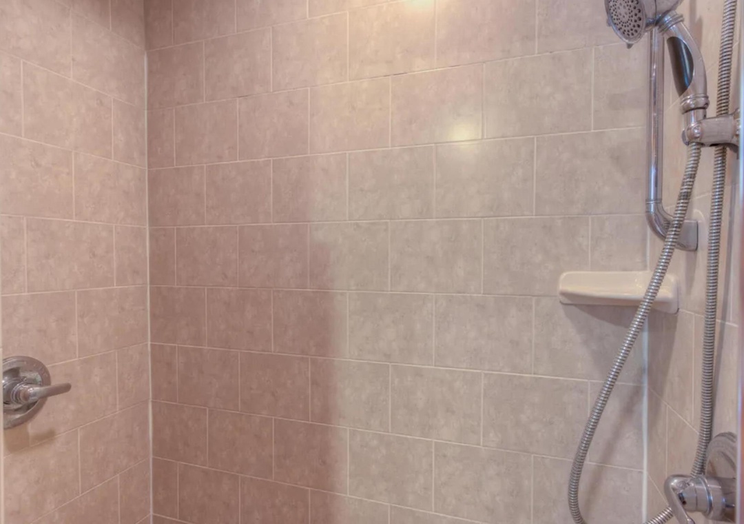 Step into your private tiled shower, featuring a handheld showerhead and built-in seating for comfort and convenience during your stay.