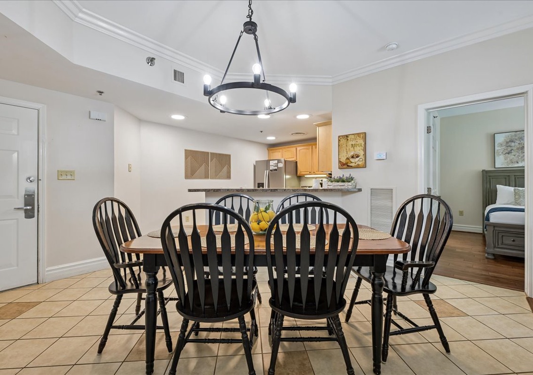 Gather your group around this inviting dining table under elegant chandelier lighting, with the modern kitchen just steps away for easy meal prep.