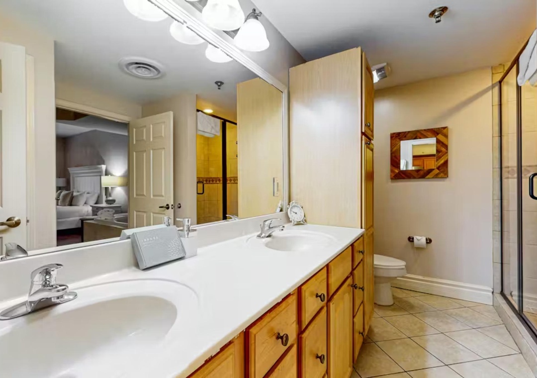Step into your spacious bathroom with dual sinks, ample cabinet storage, and a glass-enclosed shower for refreshing moments.