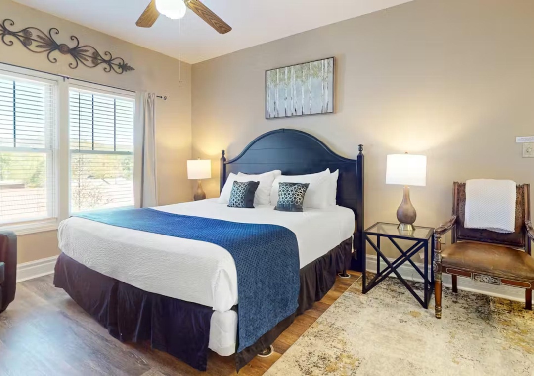 Sink into your elegant bedroom featuring a luxurious king bed with crisp linens and tasteful navy accents.