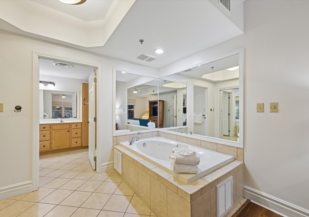 Luxurious master suite with jetted tub and mirrors - your private spa retreat awaits after busy days exploring.
