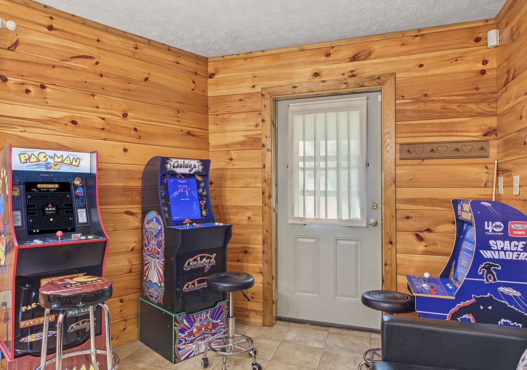 Challenge friends to classic arcade showdowns in your private game room, featuring vintage standup machines with cushioned bar stools for marathon sessions in warm wood-paneled comfort.
