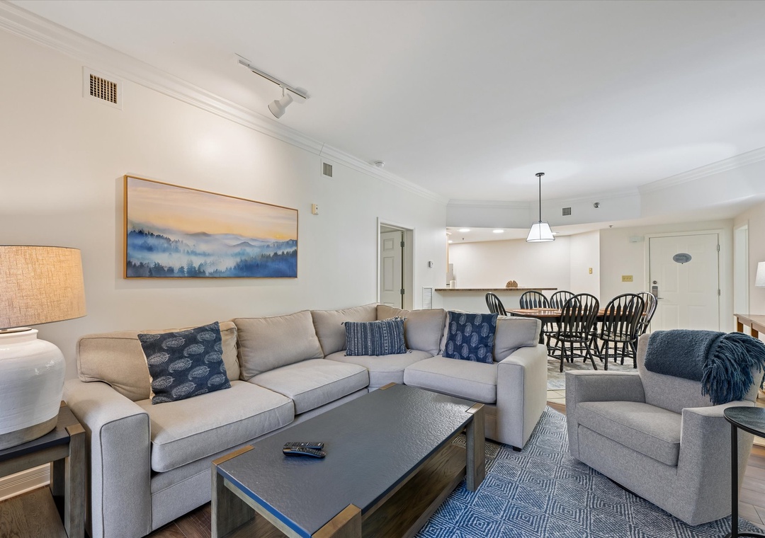 Sink into plush gray seating with mountain artwork overlooking your open kitchen and dining space, perfect for relaxing evenings.