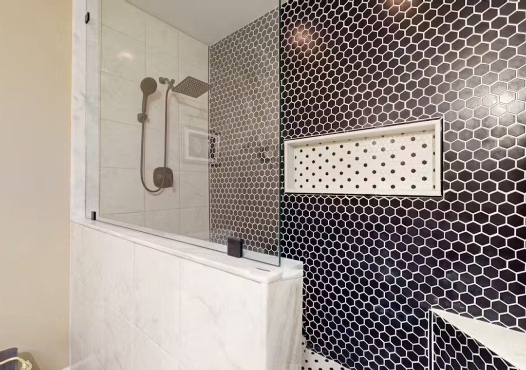Unwind in your stylish bathroom featuring stunning hexagonal tiles and a luxurious rain shower over the tub.