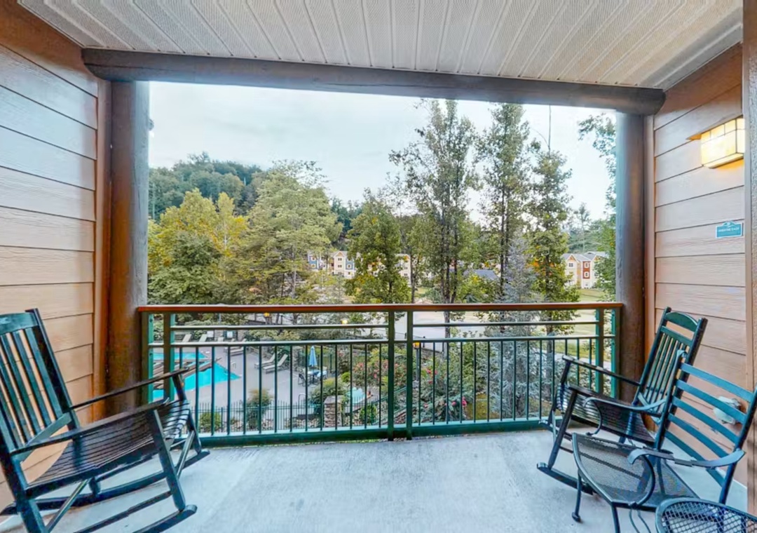 Unwind on your private balcony with comfortable rocking chairs overlooking lush trees and the sparkling pool below.