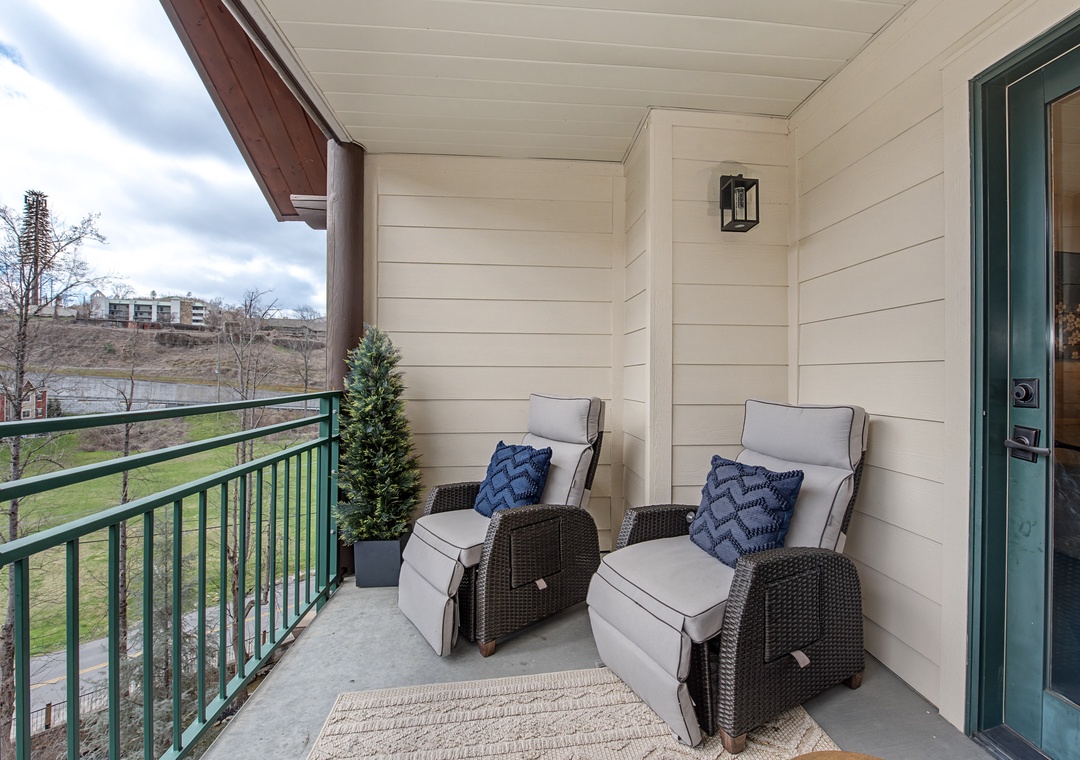 Your private balcony awaits with plush recliners and blue accent pillows, perfect for morning coffee or evening relaxation.
