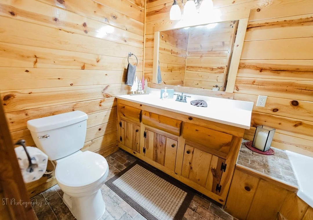 Unwind in this warm, rustic cabin bathroom featuring pine walls, a spacious vanity, and all the essentials for your mountain escape.