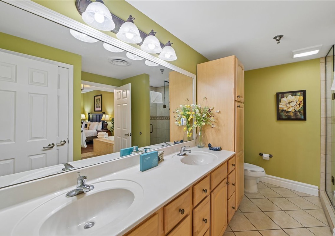 Step into your spacious bathroom with dual sinks, ample storage, and cheerful green walls that create a refreshing morning routine.
