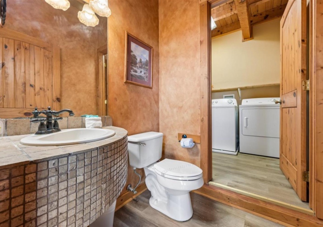 Rustic bathroom with custom tile vanity, fresh towels, and convenient in-unit laundry access—everything you need for a comfortable stay in this charming mountain retreat.