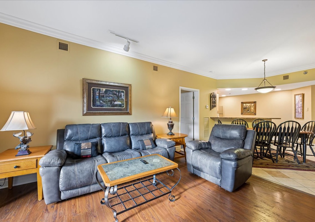 Relax in your spacious living room featuring plush leather recliners and warm golden walls that create a cozy atmosphere for unwinding.