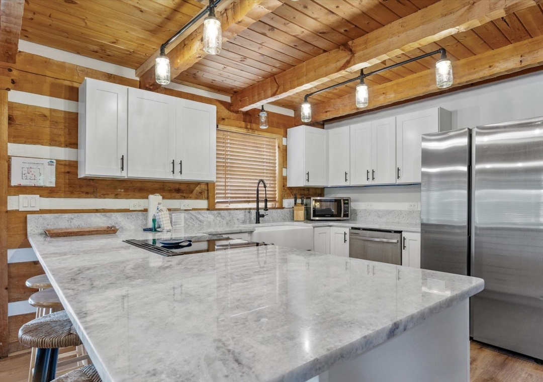 Your gourmet kitchen blends rustic warmth with modern luxury—marble countertops gleam under Edison bulb lighting while exposed beams create cozy charm.