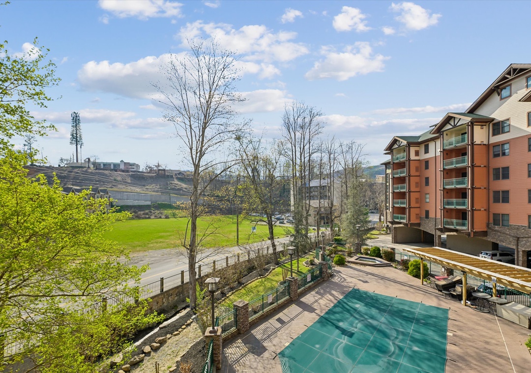 Modern apartment complex with outdoor pool and recreational areas set against city skyline backdrop.