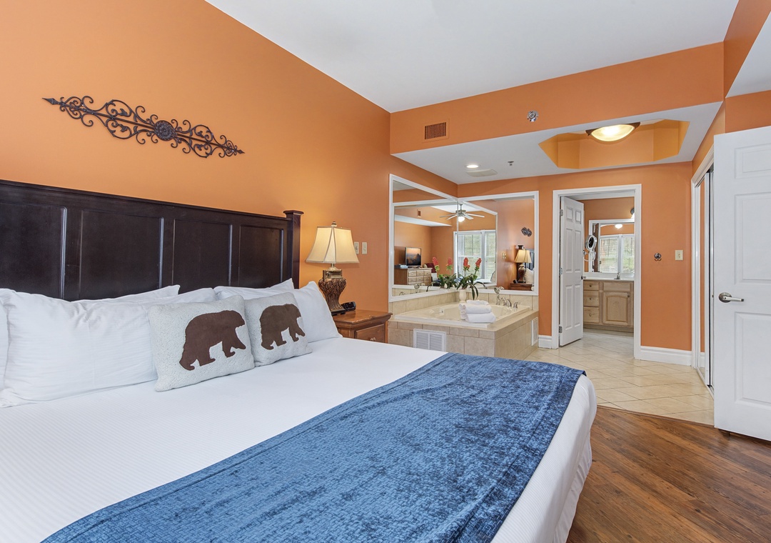 Unwind in your spacious bedroom featuring warm earth tones, whimsical bear-themed pillows, and an elegant jacuzzi tub for ultimate relaxation.